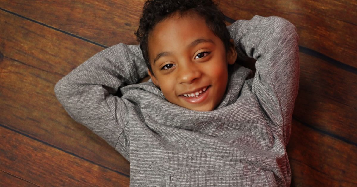 A Young Boy Striking Photography Poses On A Wooden Floor.