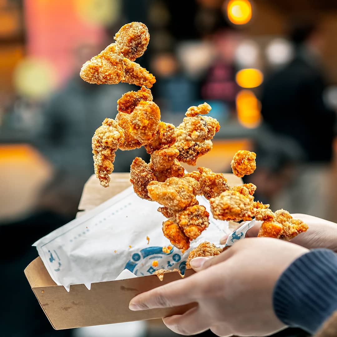 A Person Holding A Box Of Fried Chicken While Adjusting The Shutter Speed For A Perfect Food Photography Shot.