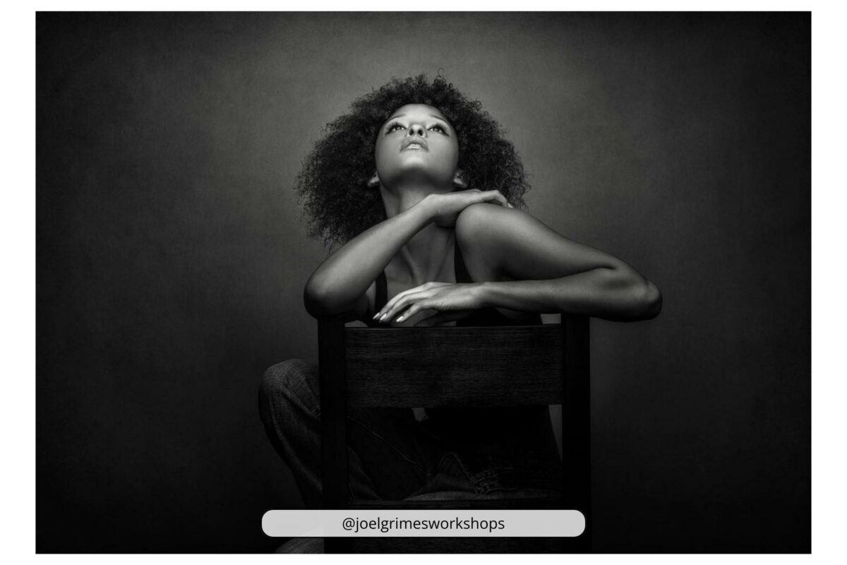 An Artistic Black And White Photo Capturing A Woman Gracefully Posing On A Chair.