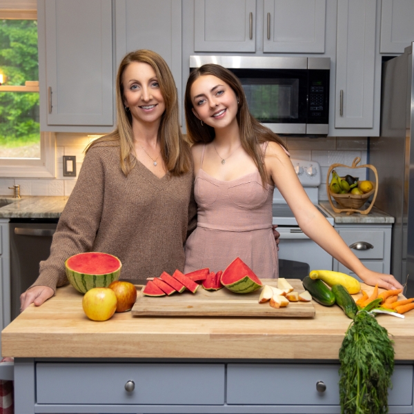 Two Women Posing In Front Of A Kitchen Counter.