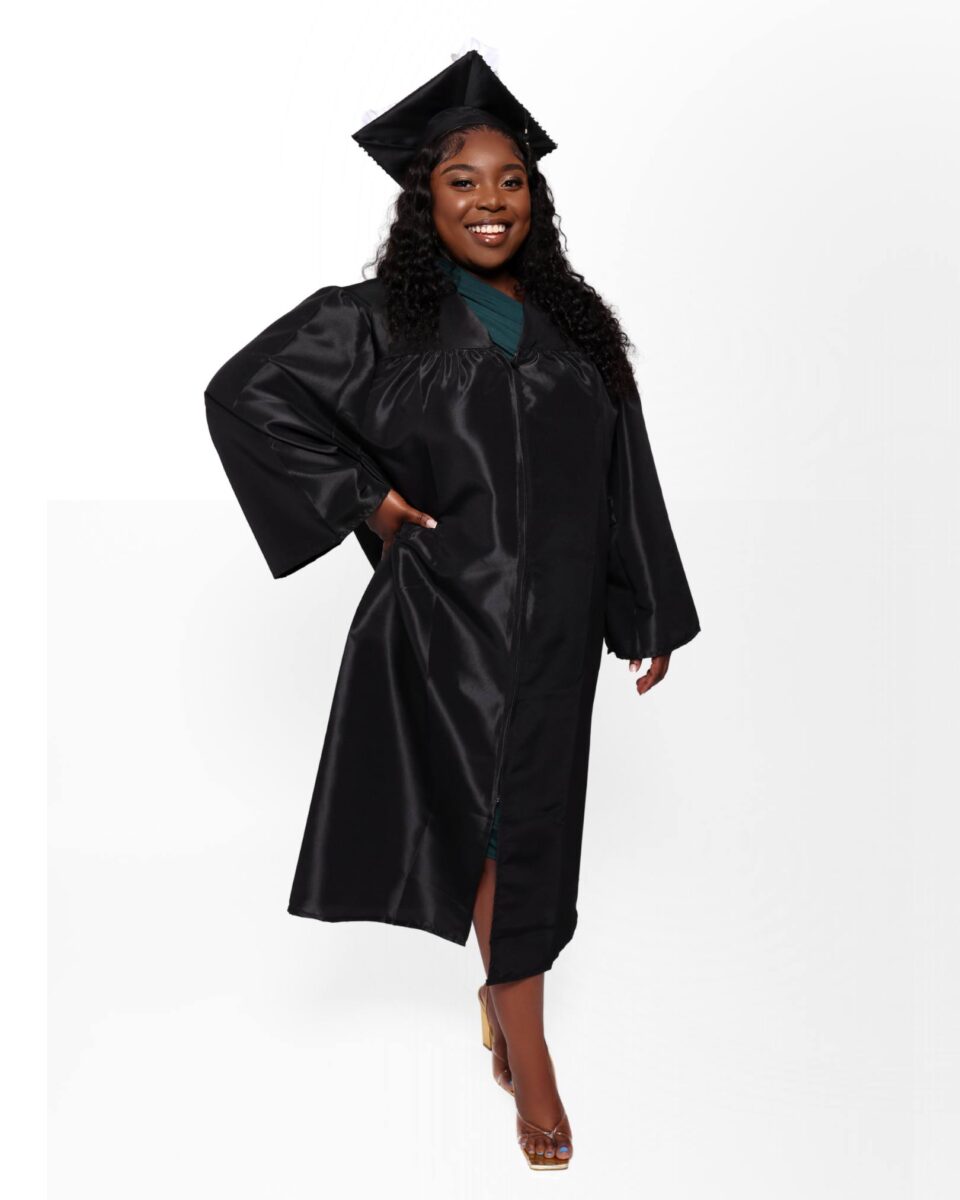 A Woman Wearing A Black Graduation Cap And Gown Stands And Smiles At The Camera Against A Plain White Background, Representing The Proud Achievements Celebrated By Red October Firm.