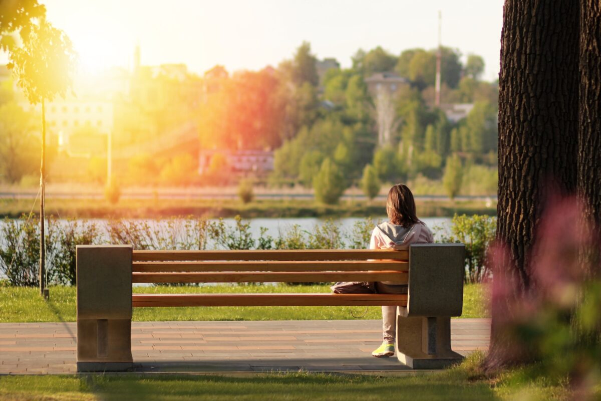 A Woman Sitting On A Bench, Beautifully Captured In A Composition In Photography.
