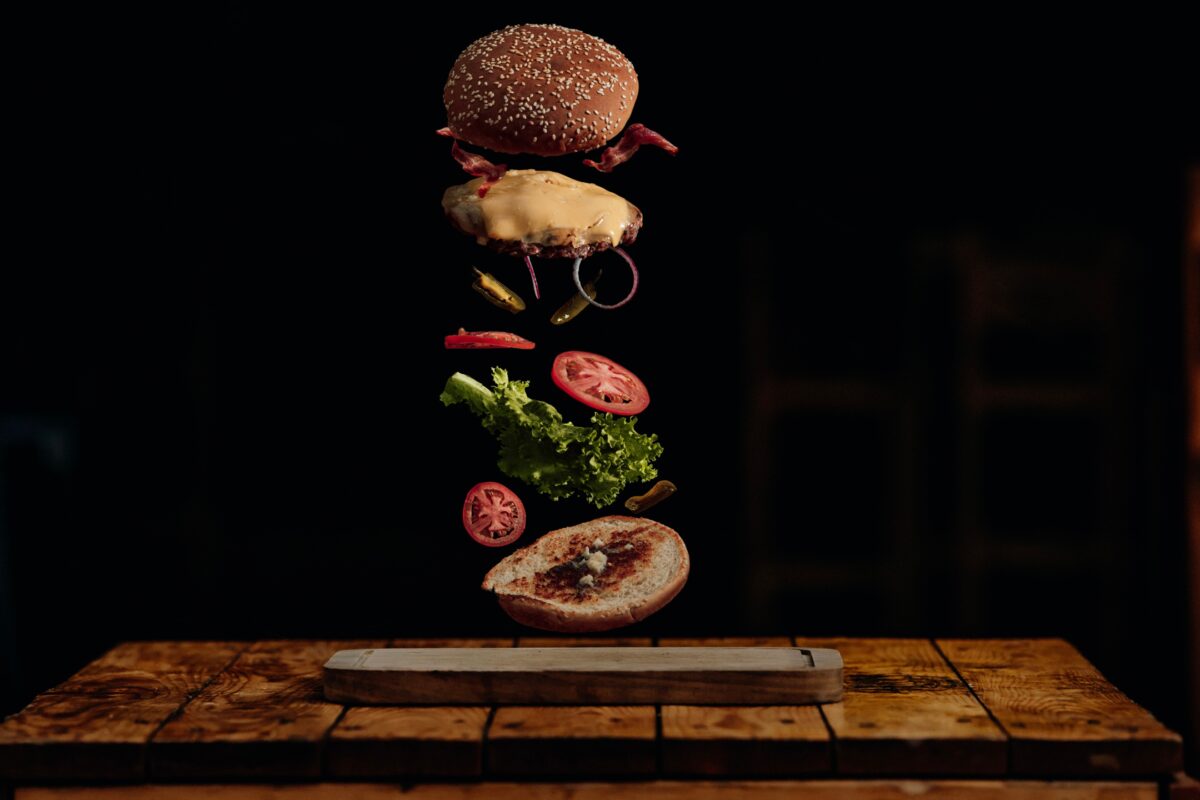 An Image Capturing The Moment A Burger Falls Off A Wooden Table, Highlighting The Significance Of Photography.