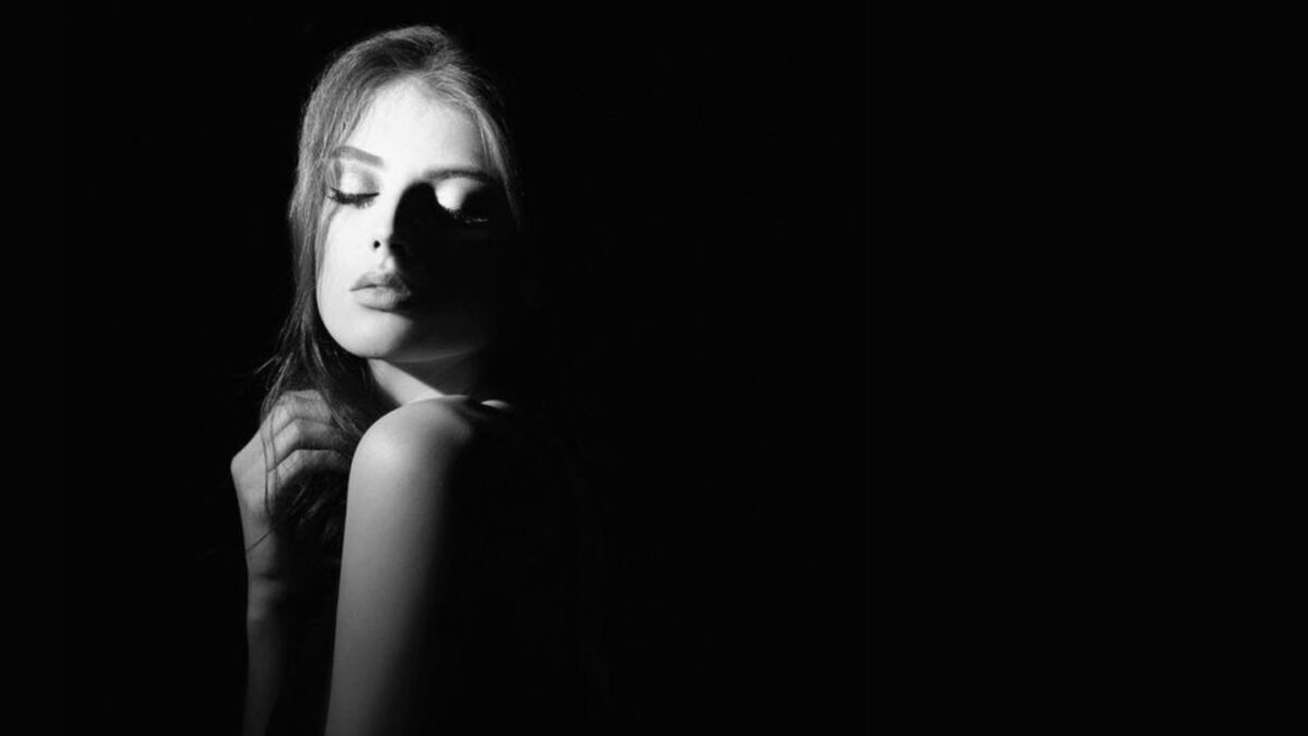 A Black And White Photo Of A Woman Posing In The Dark, Showcasing Shadow Photography.