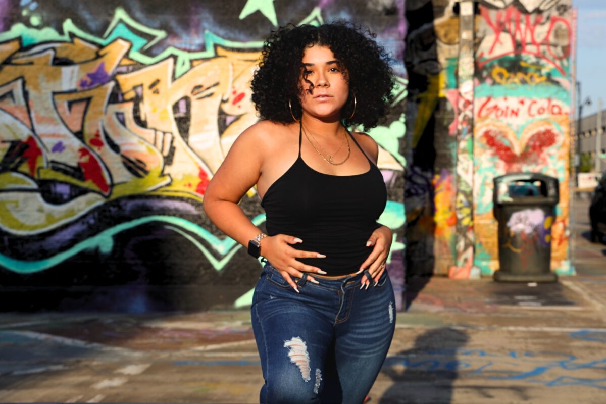 A Woman Showcasing Her Artistic Side In Front Of A Graffiti-Covered Wall.