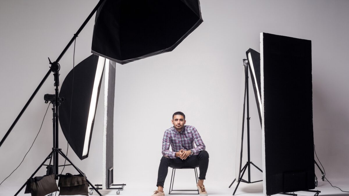 A Man Sitting On A Chair In Front Of A Photography Lighting Kit.