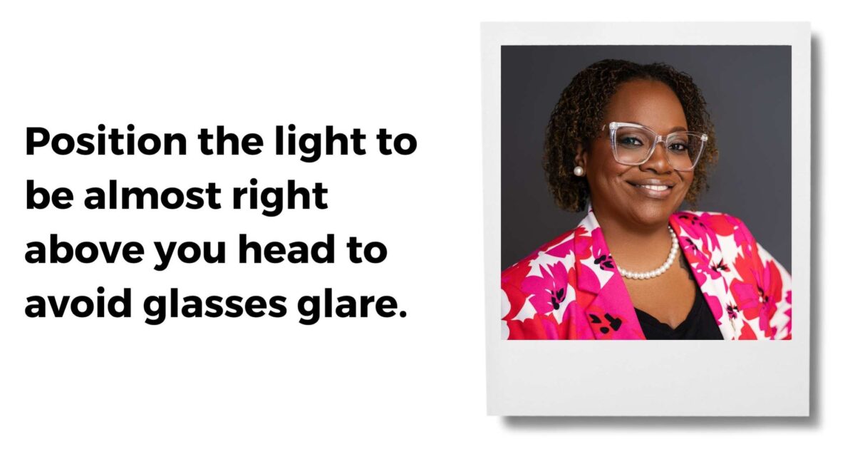 A Smiling Person Wearing Glasses And A Pink Floral Blazer, With Text Advising To Position Light Above One'S Head To Avoid Glasses Glare.